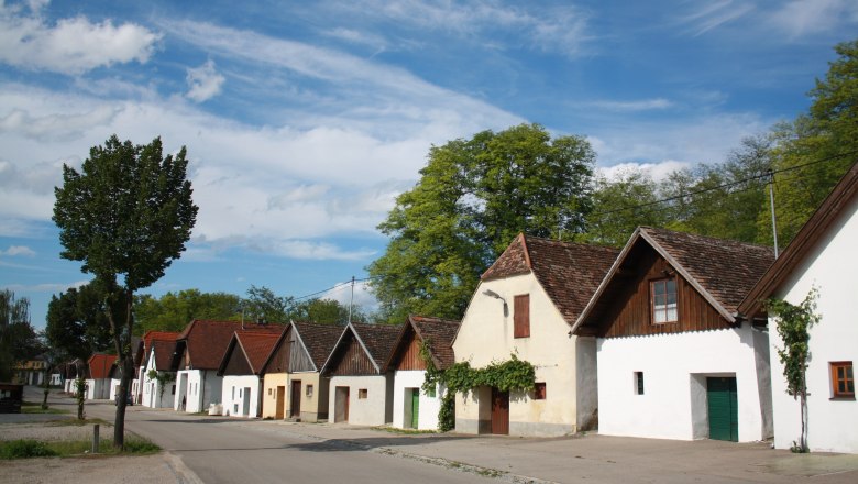 Reihe von traditionellen Weinkellern in Jetzelsdorf unter blauem Himmel.