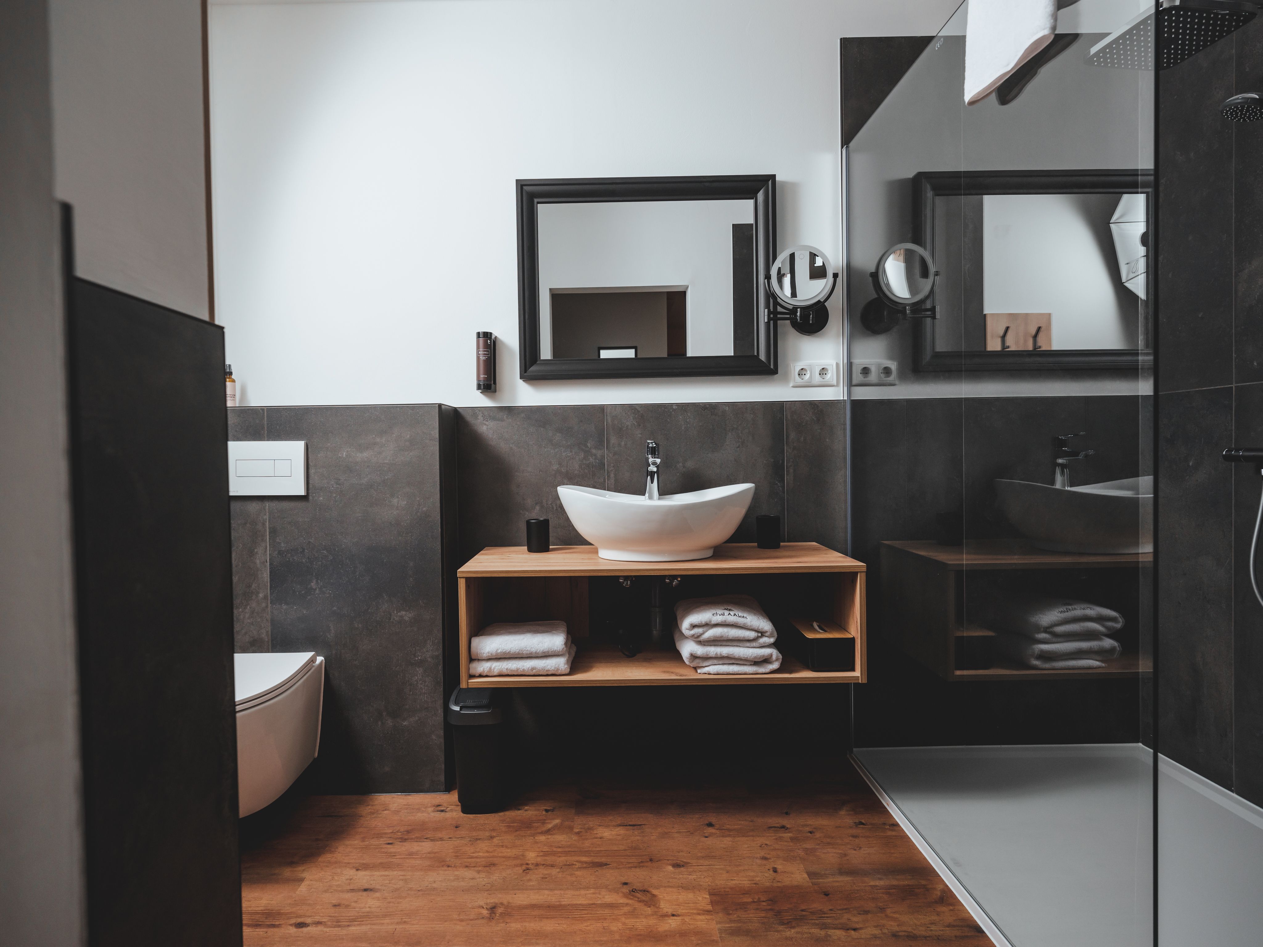 Modernes Badezimmer mit Waschbecken, Spiegel, Toilette und Dusche.