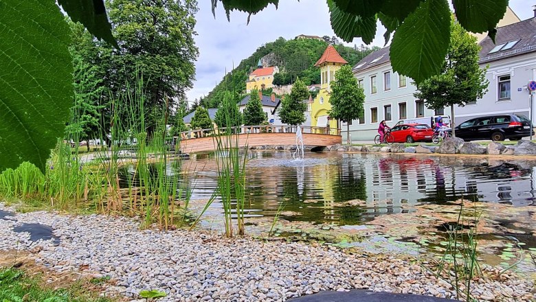 Ausblick von einen Park mit Teich und Br&uuml;cke auf die Bergkirche Pitten