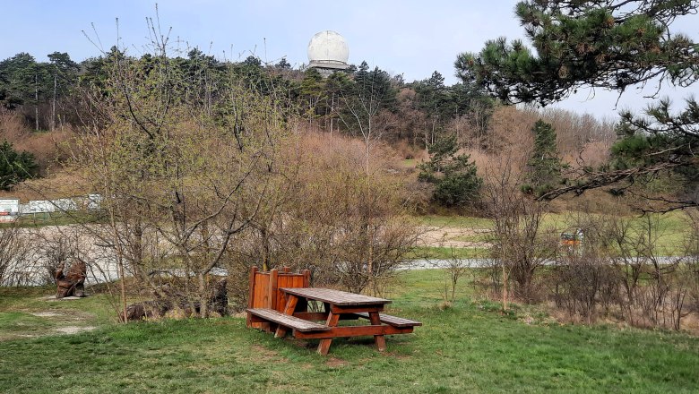 Wohnmobilstellplatz, © Bernhard Zechner Picknicktisch auf einer Wiese mit Bäumen und einem großen weißen Radom im Hintergrund.