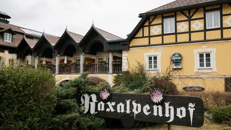 Ein traditionelles Geb&auml;ude mit gelber Fassade und einem Schild mit der Aufschrift 'Raxalpenhof'.