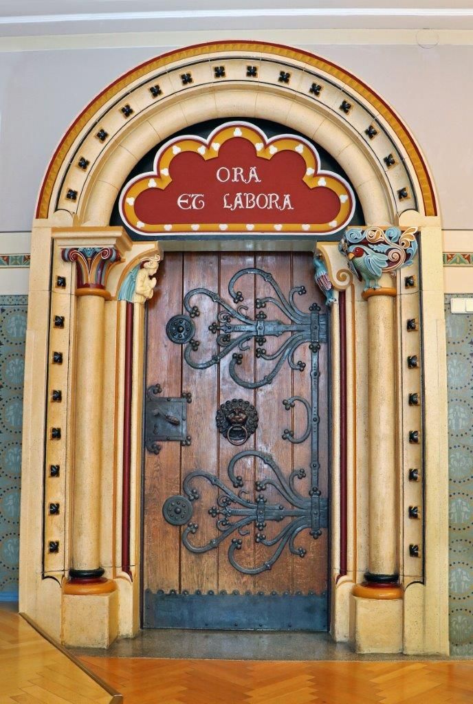 Verzierte Holztür mit lateinischer Inschrift 'Ora et Labora'.