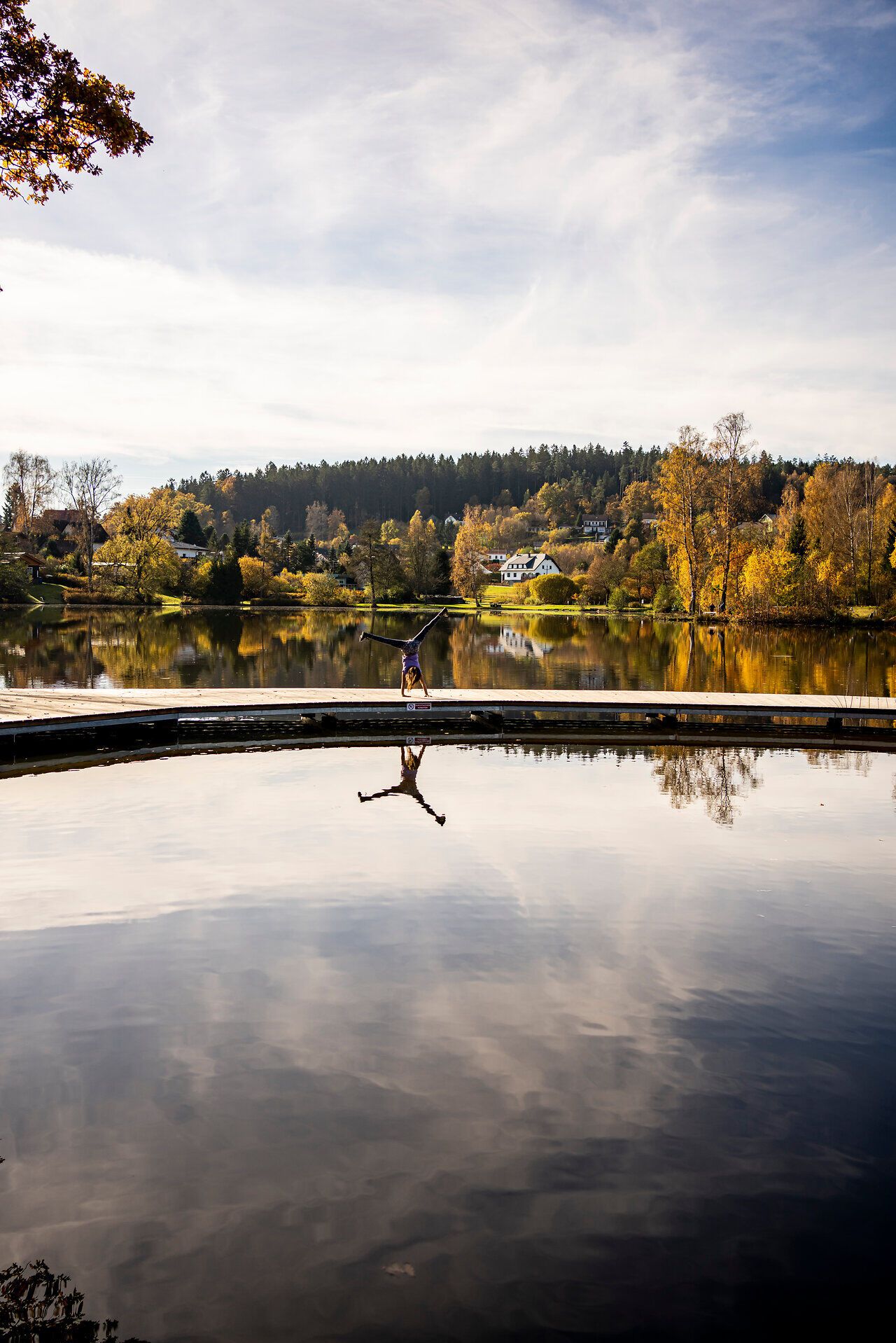 Die sanften Hügel spiegeln sich im ruhigen Wasser, während die bunten Blätter der Bäume im goldenen Licht des Herbstes leuchten. Ein Ort der Ruhe und Inspiration, ideal für einen entspannten Aufenthalt in der Natur.
