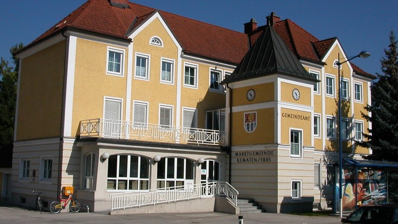 Gelbes Geb&auml;ude des Gemeindeamts Kematen an der Ybbs mit Uhr und Wappen.