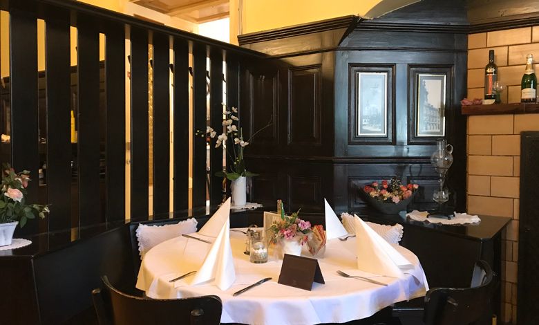 Ein gemütlicher Tisch in einem traditionellen Restaurant mit dunkler Holzvertäfelung und dekorativen Blumen.