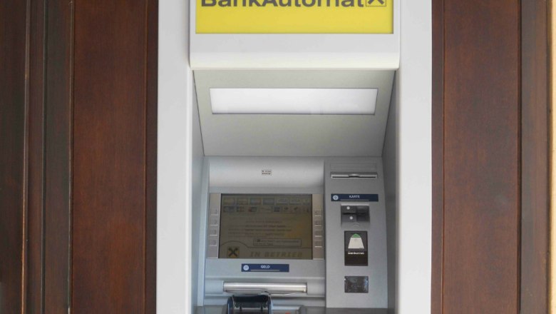 Ein Bankautomat mit gelbem Schild und Raiffeisen-Logo.