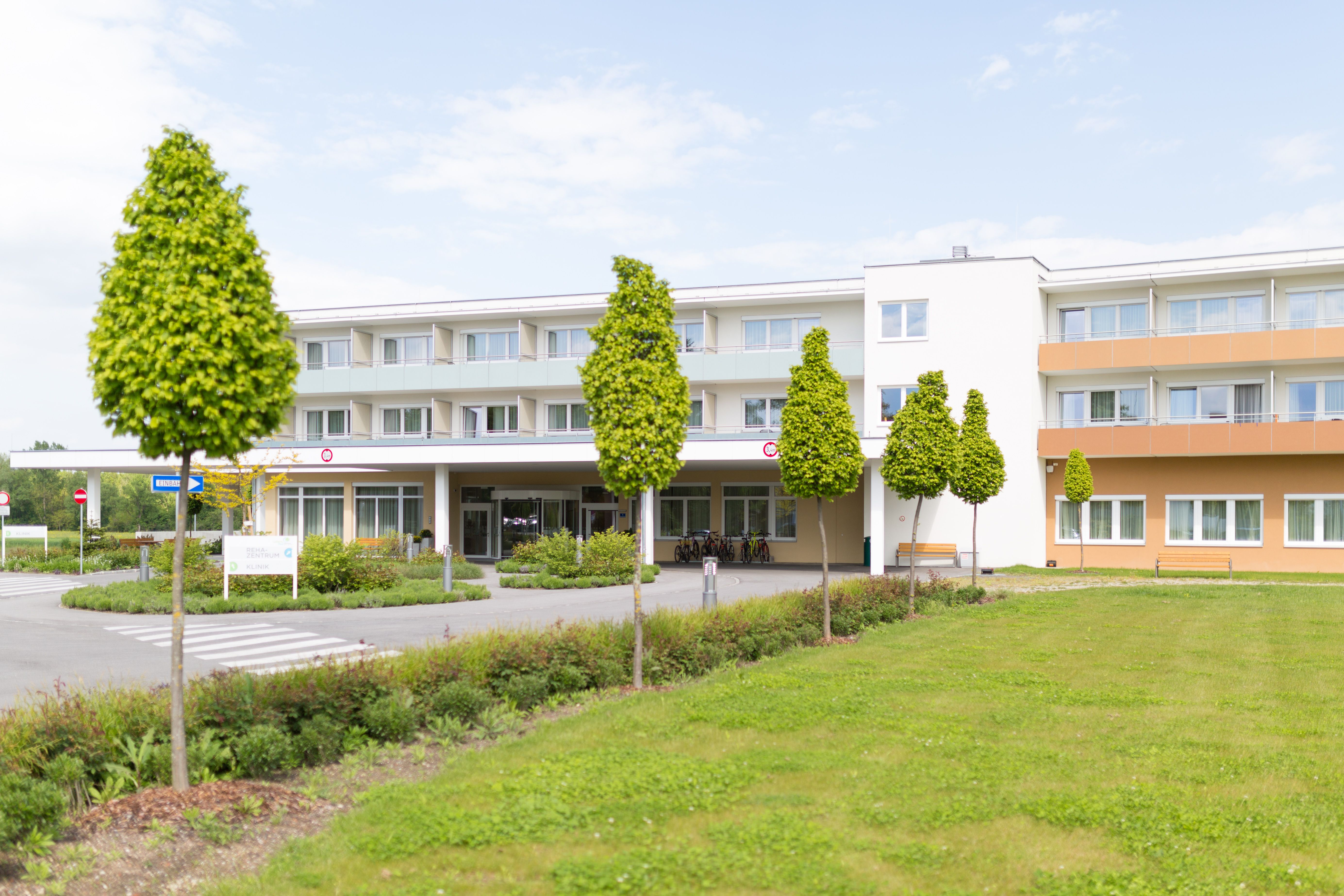 Außenansicht eines modernen Gebäudes mit Bäumen und Rasenfläche.