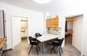 Moderner Essbereich mit Tisch, schwarzen St&uuml;hlen und Holzschr&auml;nken.