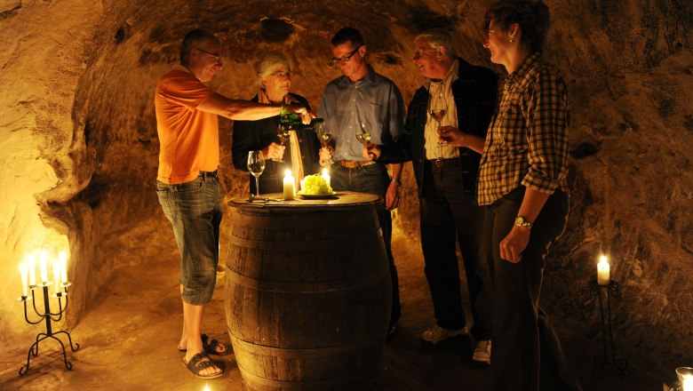 Gruppe von Menschen in einem Weinkeller, die Wein probieren.