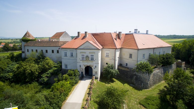Luftaufnahme von Schloss Mailberg mit roten Dächern und umgebender Landschaft.
