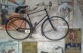 Altes Fahrrad an einer Wand mit Vintage-Werbeplakaten im Fahrradmuseum Schloss Vösendorf.