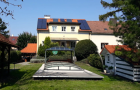 Ein Haus mit Solarpanelen und einem &uuml;berdachten Pool im Garten.