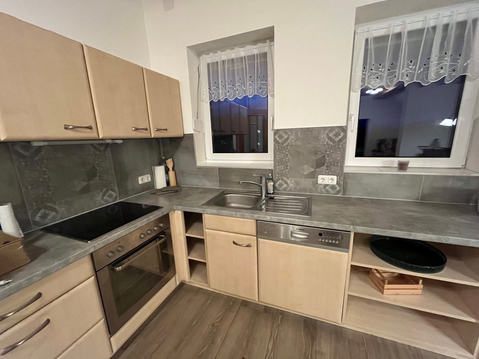 Moderne Küche mit Holzschränken, Elektroherd, Spüle und Geschirrspüler.