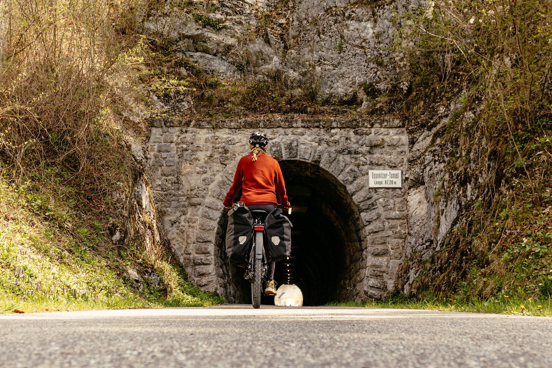 Ein Radfahrer genießt die frische Bergluft und die atemberaubende Natur, während er auf dem Ybbstalradweg in die Tiefe eines alten Tunnels fährt. Umgeben von üppigem Grün und majestätischen Felsen, wird die Fahrt zu einem unvergesslichen Erlebnis in der idyllischen Landschaft des Mostviertels.