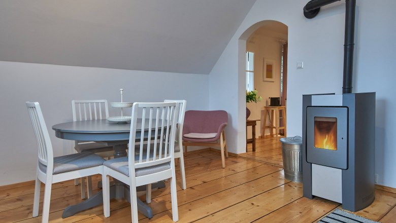 Gem&uuml;tliches Wohnzimmer mit Esstisch, St&uuml;hlen, Sessel und Kamin.