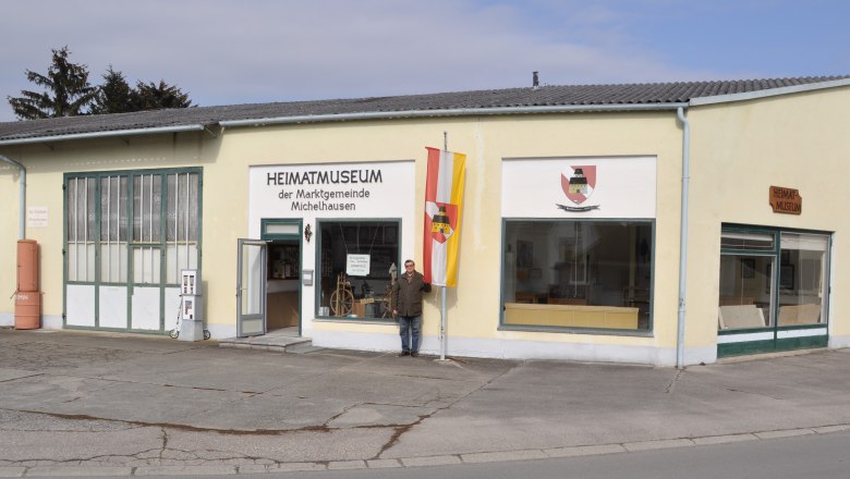 Außenansicht des Heimatmuseums Michelhausen mit gelbem Gebäude und Flagge.