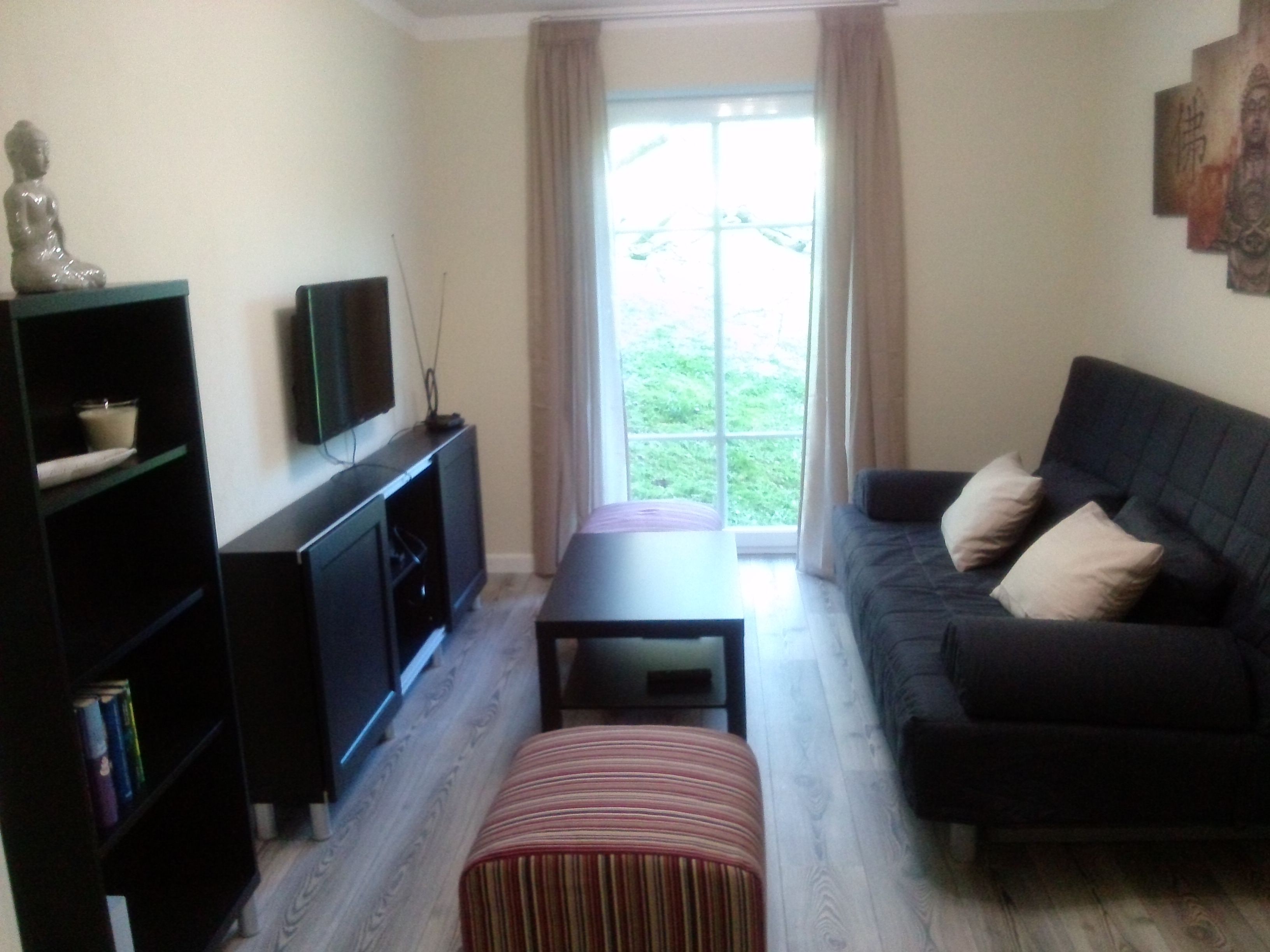 Modernes Wohnzimmer mit Sofa, Couchtisch, Fernseher und Bücherregal.