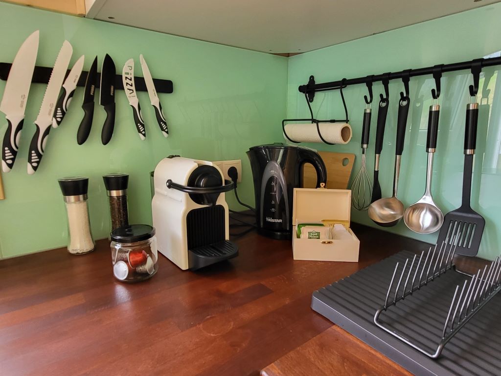 Küchenarbeitsplatte mit Kaffeemaschine, Wasserkocher, Gewürzmühlen und Küchenutensilien.