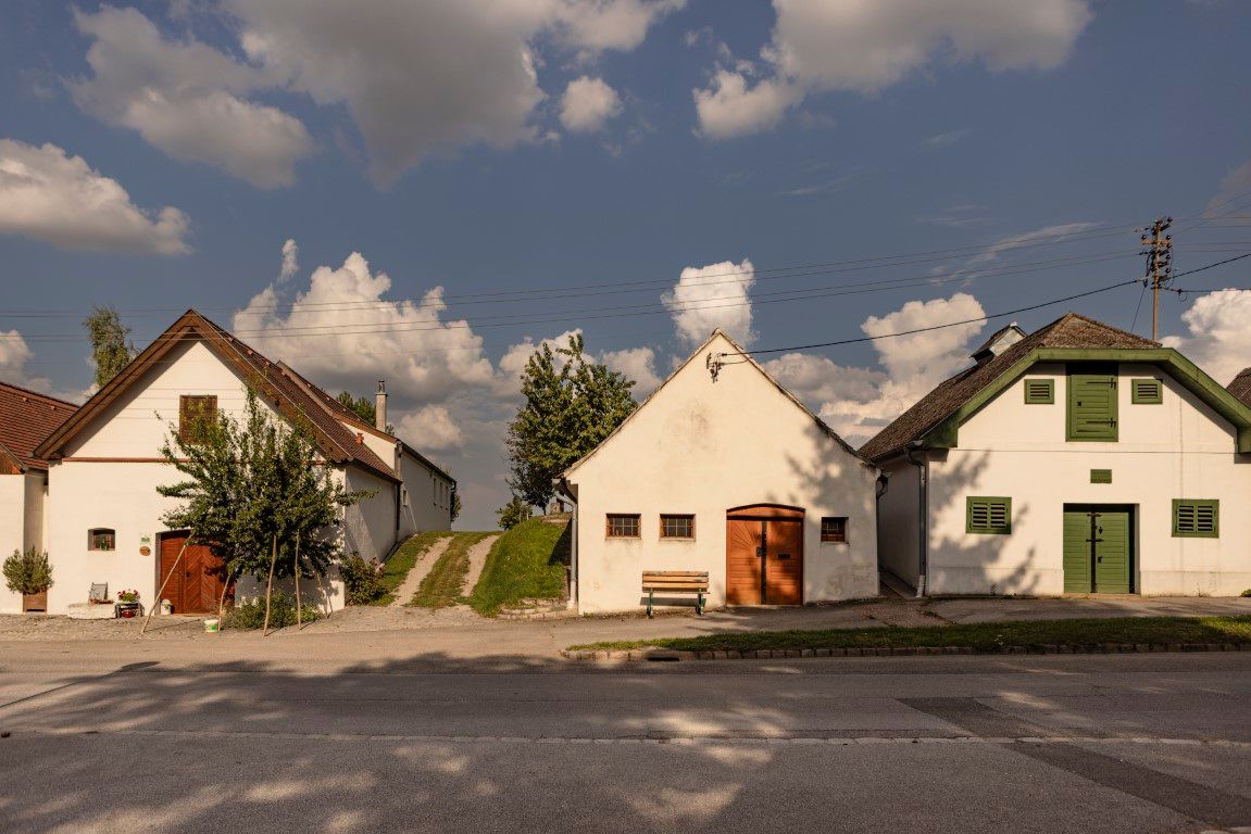 Drei traditionelle Kellerhäuser in Kettlasbrunn unter blauem Himmel mit Wolken.