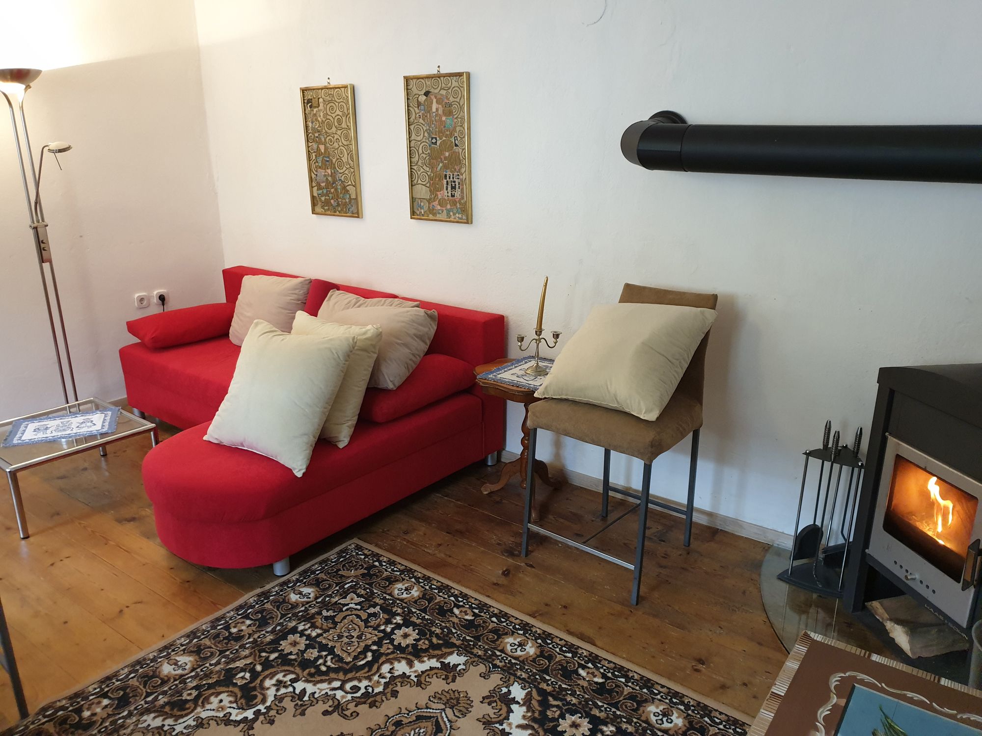 Gemütliche Wohnzimmer-Ecke mit rotem Sofa, Kamin und Teppich.