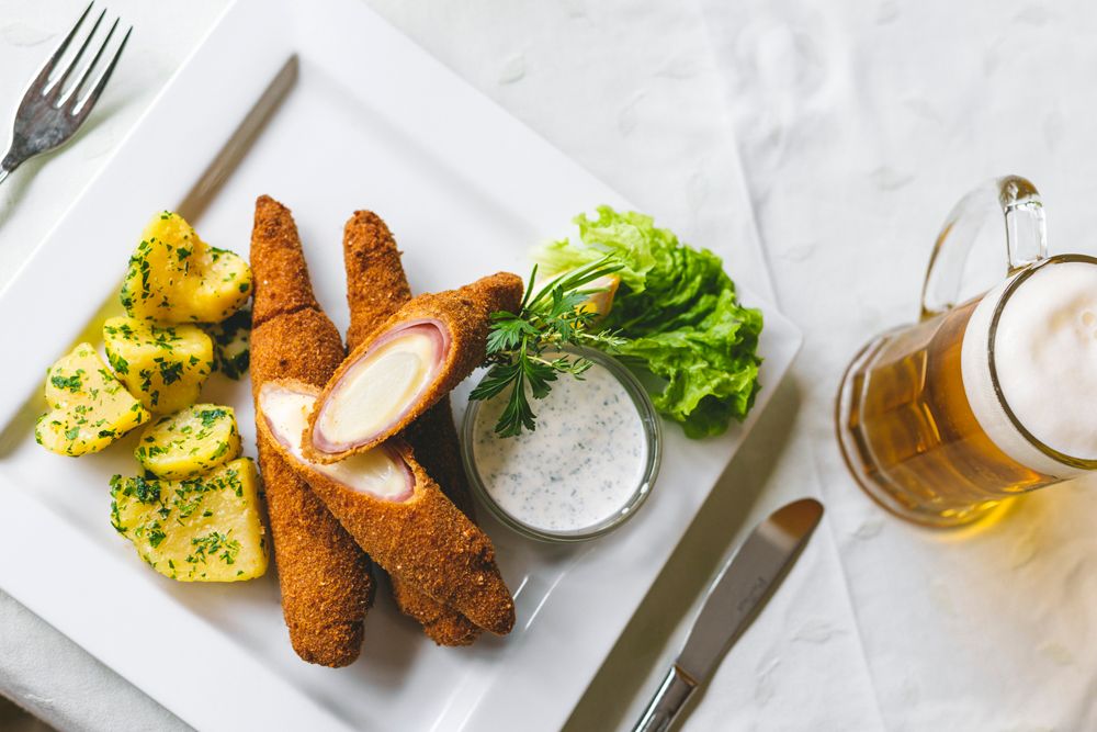 Gebackener Spargel mit Kartoffeln, Salat und Bier auf weißem Teller.