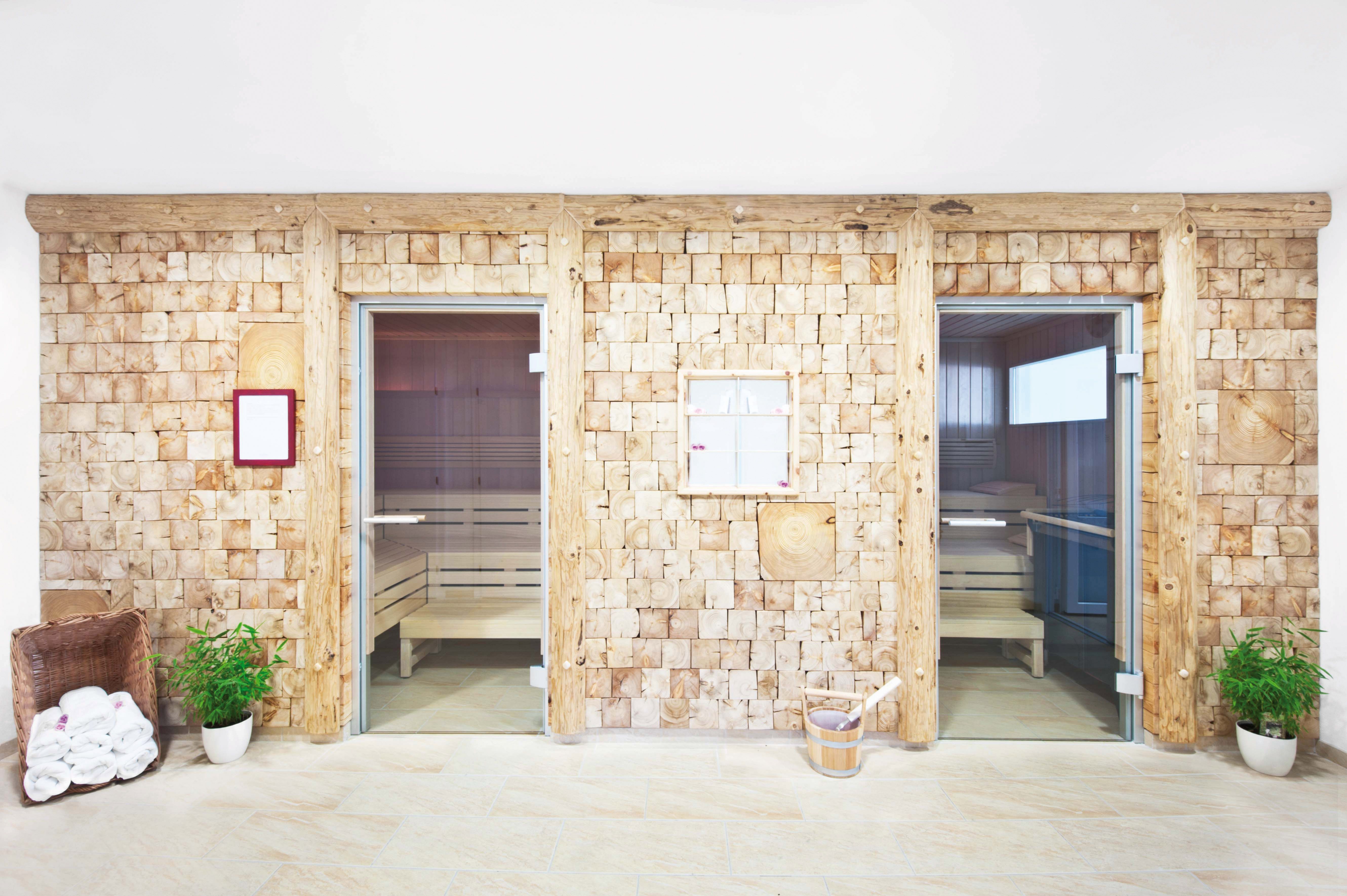 Zwei Saunakabinen mit Holzwänden und Glastüren in einem Wellnessbereich.