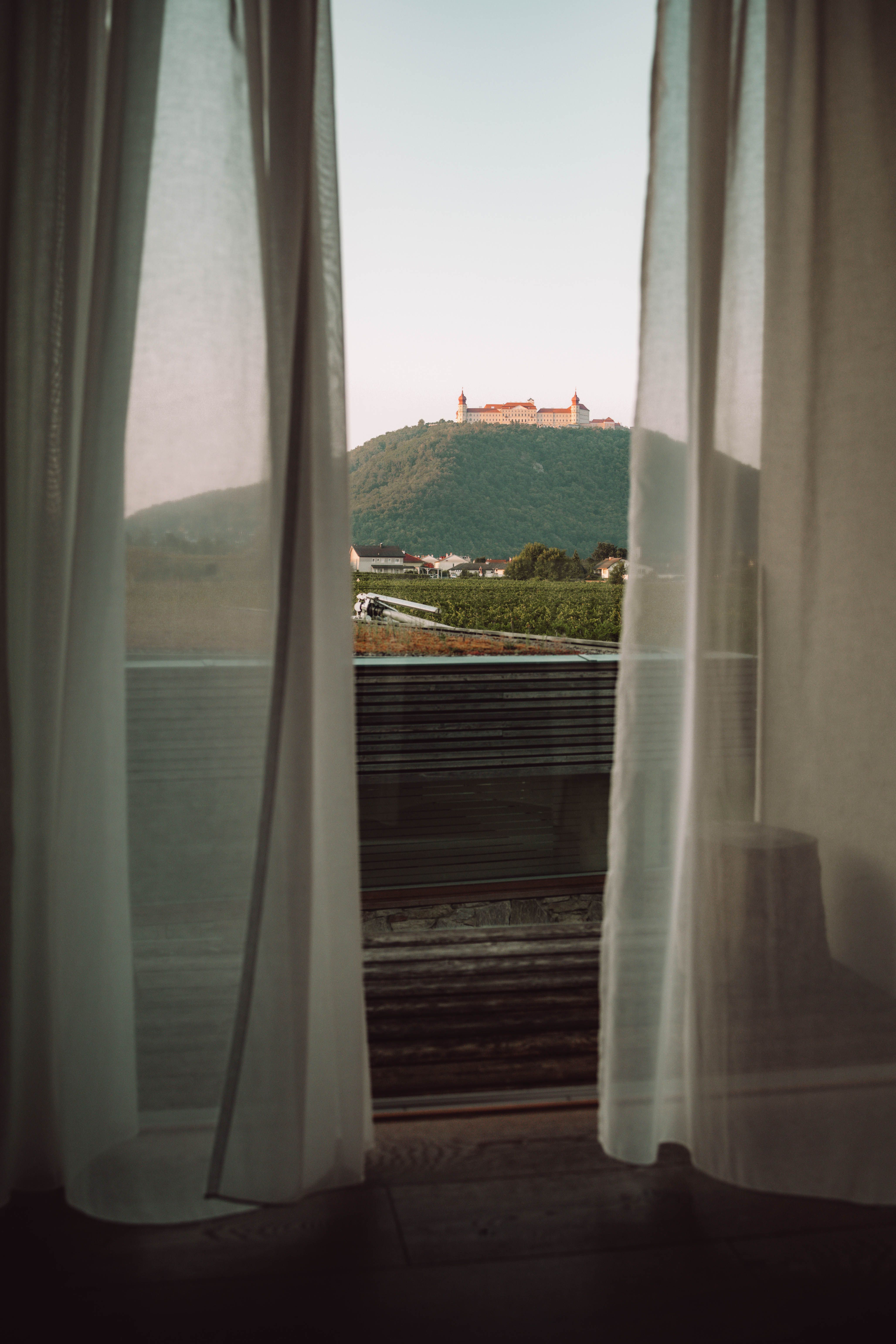 Außenansicht des MALAT Weinguts und Hotels mit moderner Architektur und einem Fahrzeug im Vordergrund.