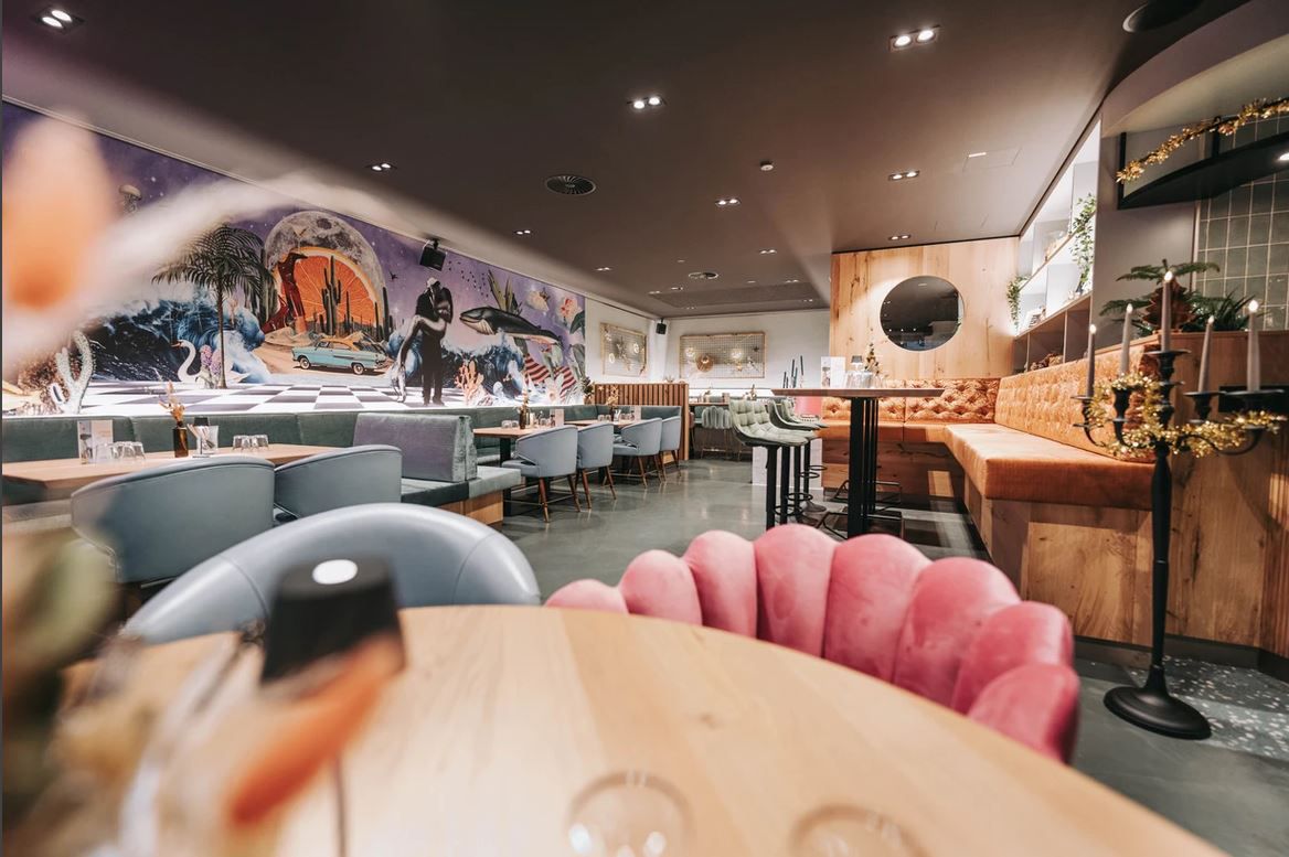 Innenansicht eines stilvollen Restaurants mit moderner Einrichtung und Wandkunst.