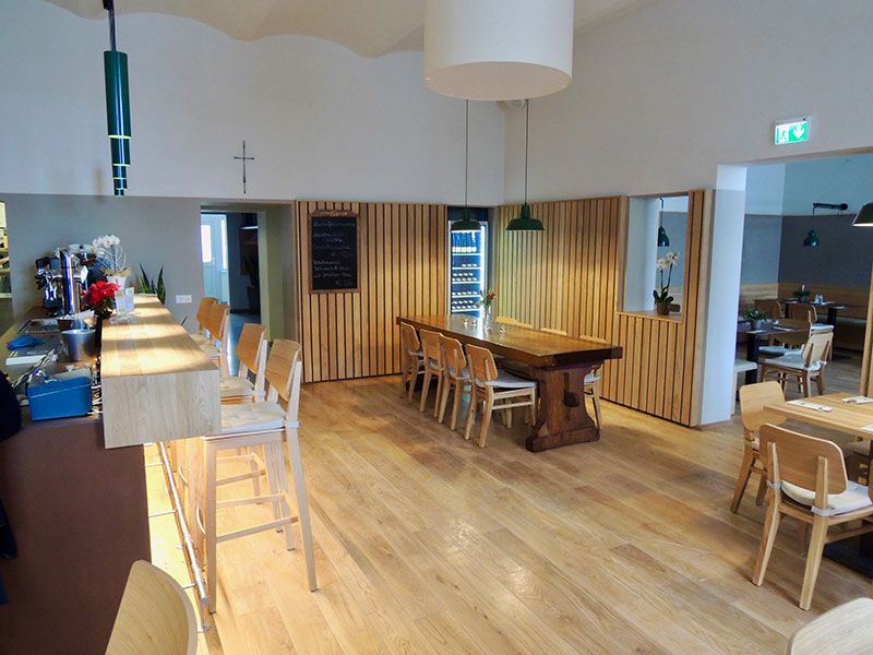 Innenansicht eines modernen Gasthauses mit Holzmöbeln und Theke.