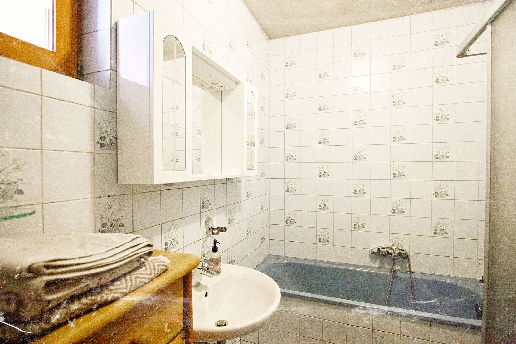 Ein Badezimmer mit blauen Fliesen, einer Badewanne, einem Waschbecken und einem Spiegel.
