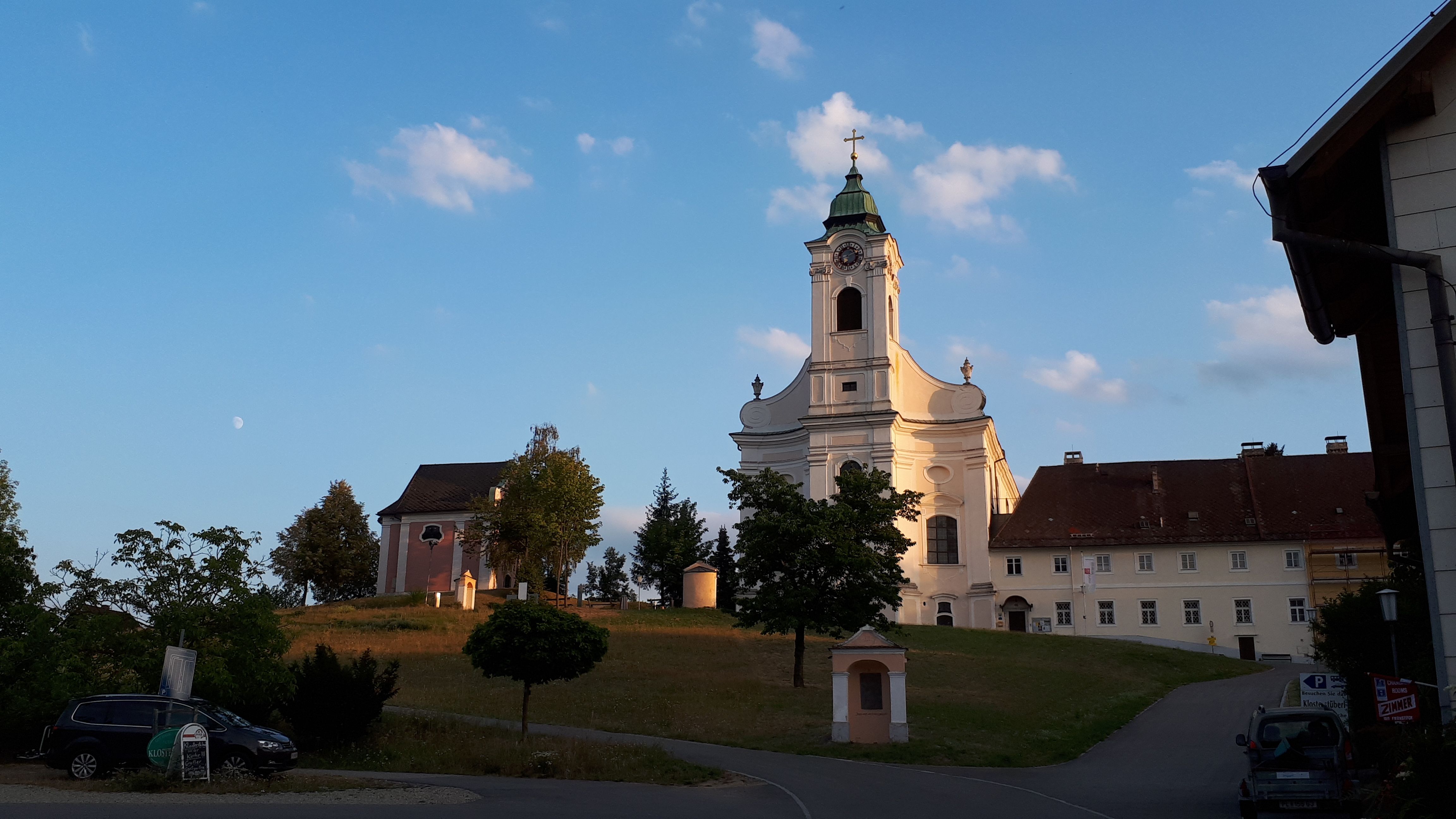 Kirche mit Turm und umliegenden Gebäuden bei Sonnenuntergang.