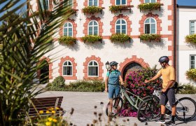 Die malerische Kulisse des Rathauses in Waidhofen l&auml;dt Radfahrer dazu ein, eine wohlverdiente Pause einzulegen. Bunte Blumenbeete umrahmen den Platz und schaffen eine einladende Atmosph&auml;re, die den Sommer in den Bergen perfekt widerspiegelt.