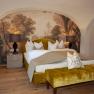 Elegante Suite mit gelbem Bett, Wandgemälde und Holzfußboden im Schloss Luberegg