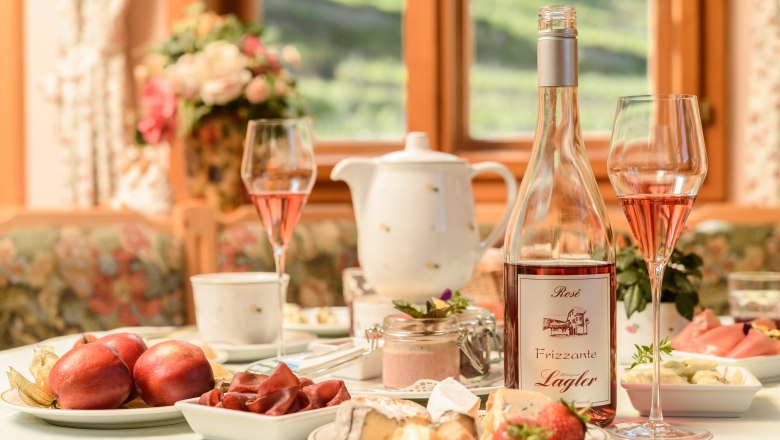 Frühstückstisch mit Obst und Käse und einer Flasche Frizzante