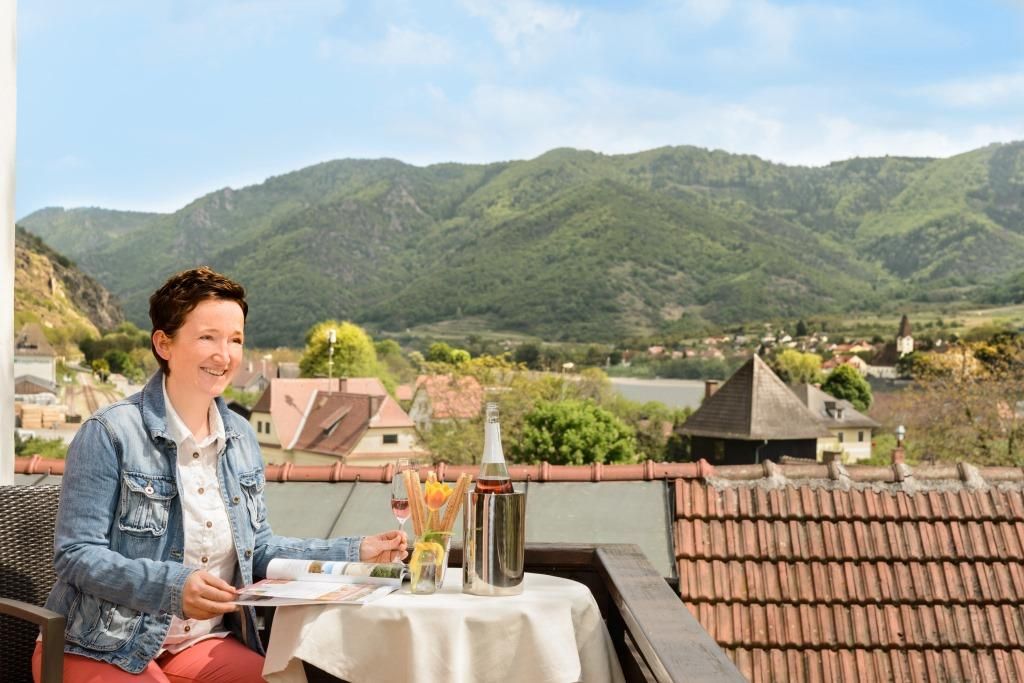 Frau auf Balkon mit Blick auf Berge und Dorf.