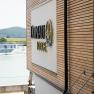 Gebäude mit Holzverkleidung und Schriftzug 'Donau Lodge', im Hintergrund die Donau und ein Schiff.