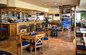 Innenansicht eines gemütlichen Lokals mit Holzmöbeln und Barbereich.