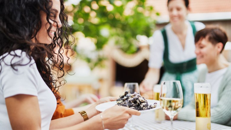 Personen genie&szlig;en Essen und Getr&auml;nke im Freien an einem Tisch.