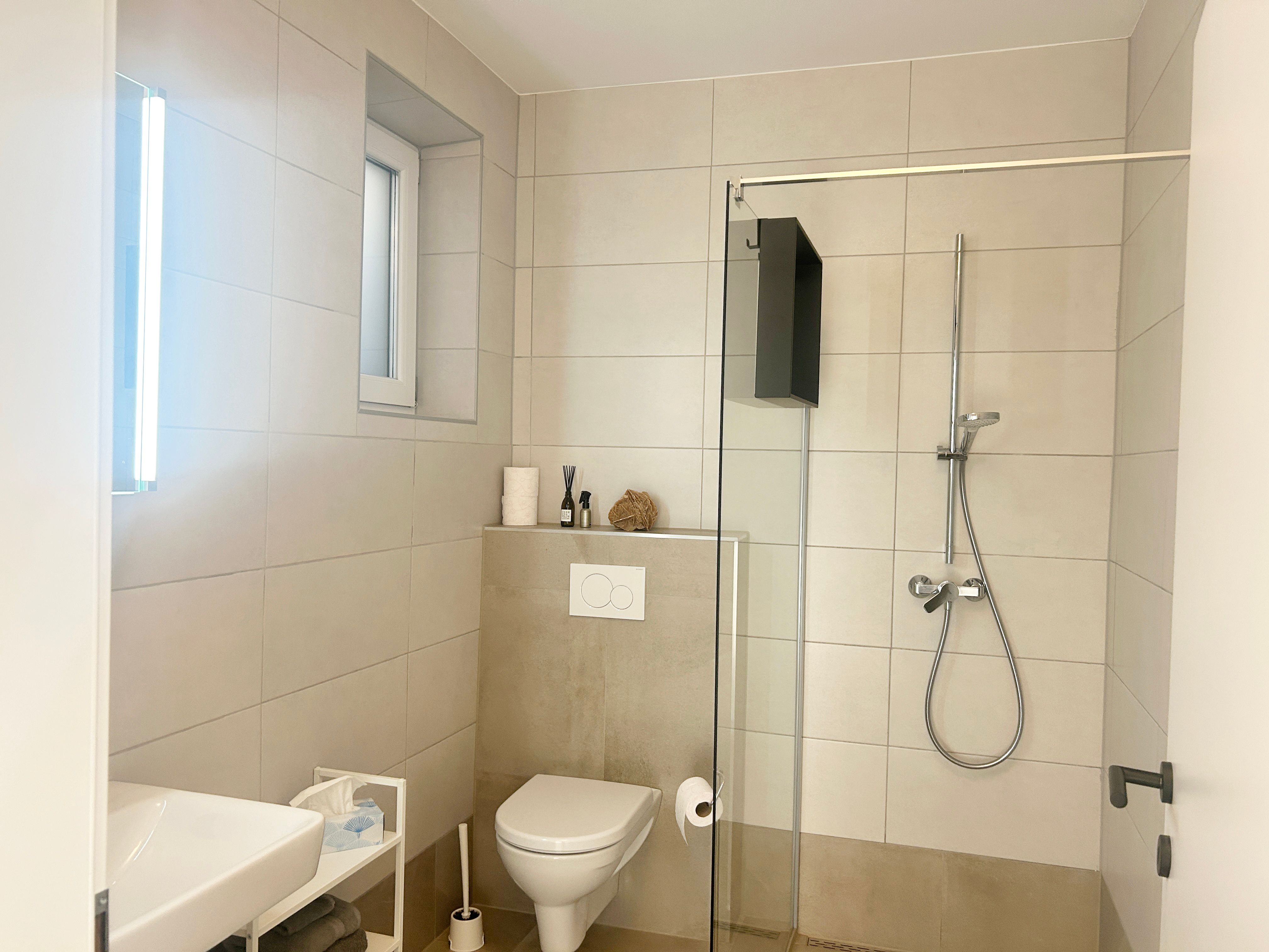 Modernes Badezimmer mit Dusche, Toilette und Waschbecken.