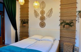 Ein gemütliches Schlafzimmer mit einem Doppelbett, dekorativen Wandteppichen und Pflanzen.