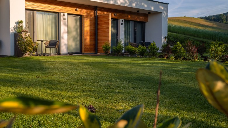 Bett in der Wies‘n, © Niederösterreich Werbung / Maximilian Pawlikowsky Modernes Gebäude mit Holzverkleidung und Terrasse in grüner Landschaft.