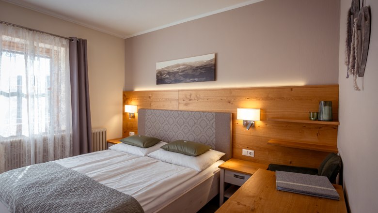 Gem&uuml;tliches Schlafzimmer mit Doppelbett, Holzm&ouml;beln und Wanddekoration.