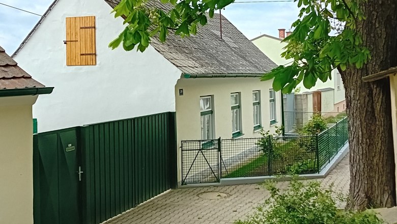 Ein traditionelles, weißes Ferienhaus mit grünem Zaun und Baum im Vordergrund.