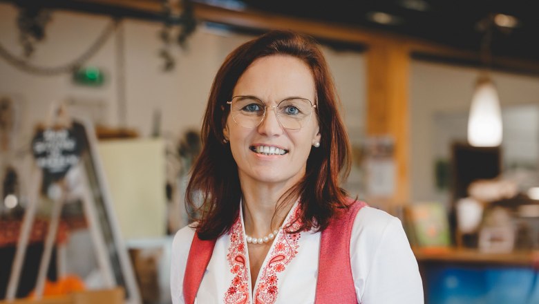 Frau in traditioneller Tracht serviert ein Gericht in einem Restaurant.