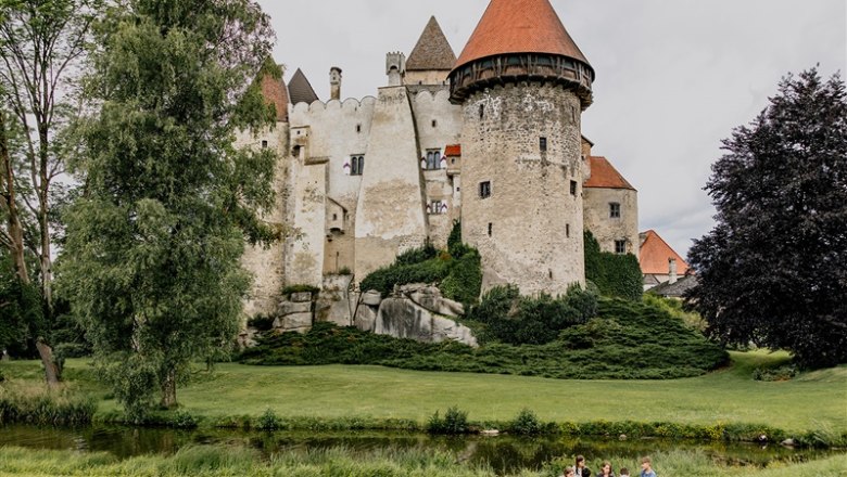 Burg Heidenreichstein mit Menschen auf einer Wiese im Vordergrund.