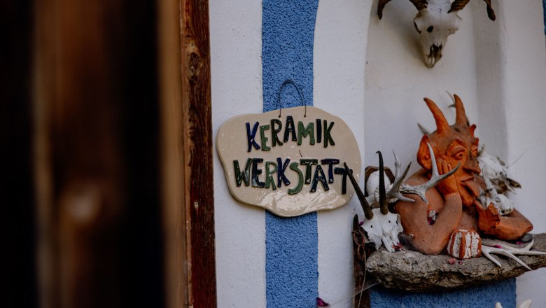 Eingang zu einer Keramikwerkstatt mit einem Schild und dekorativen Elementen.