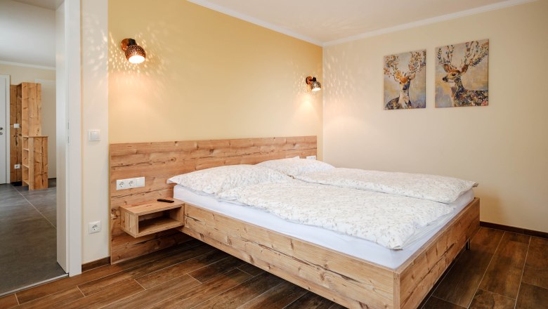 Gemütliches Schlafzimmer mit Holzbett und Hirschbildern an der Wand.