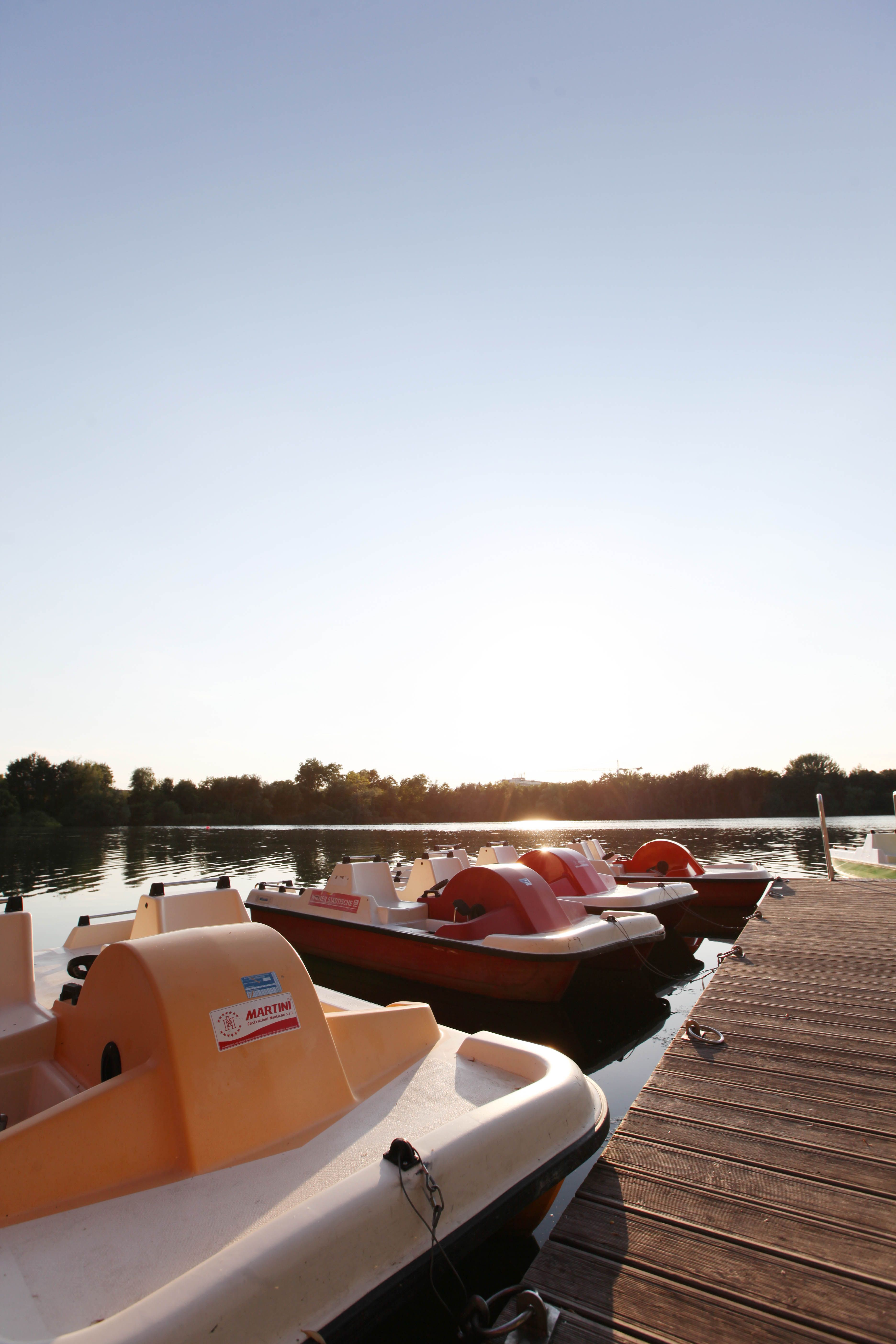 Tretboote am Steg bei Sonnenuntergang.