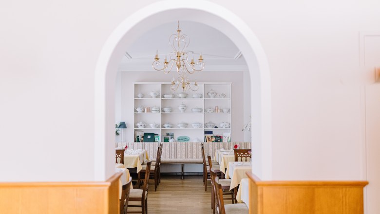 Innenansicht eines traditionellen Wirtshauses mit gedeckten Tischen und einem Kronleuchter.