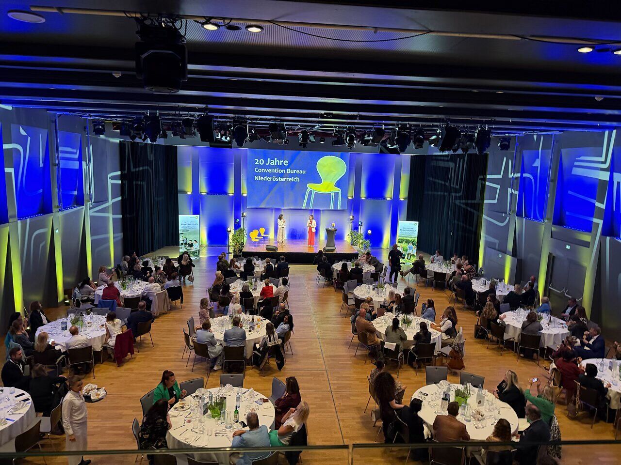 Blick in den Großen Burgsaal der Burg Perchtoldsdorf beim Galaabend zum 20-jährigen Jubiläum des Convention Bureau Niederösterreich: Zahlreiche Gäste sitzen an festlich gedeckten Tischen, auf der Bühne läuft das Jubiläumsprogramm.